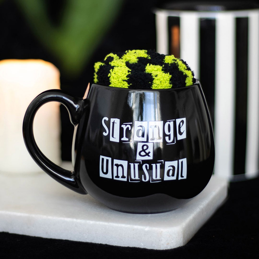 Show your spooky side with this Strange &amp; Unusual mug and Sock Set. The black rounded mug features the phrase Strange &amp; Unusual in striking letters, while the pair of fluffy green and black stripped socks adds a touch of whimsy to your wardrobe. Embrace your gothic style with this unique homeware and accessory set