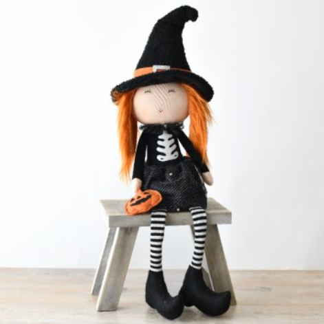 Add a touch of whimsy to your Halloween décor with this Fabric Sitting Witch With Pumpkin. This adorable witch features a black hat, orange hair, and a black and silver dress, complete with striped legs and a pumpkin detail. Perfect for adding a playful and cute element to your home