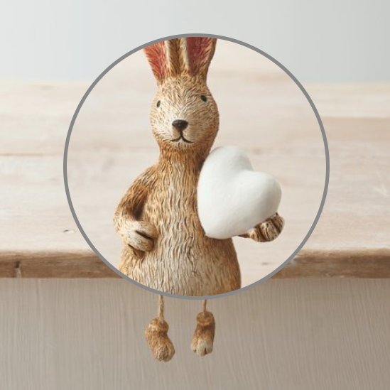 Shelf Sitting Rabbit With White Heart with dangly legs. A cute bunny figurine holding a white heart that can sit on a shelf with its legs dangling over the edge, a wonderful edition to your home decor or as a gift. 