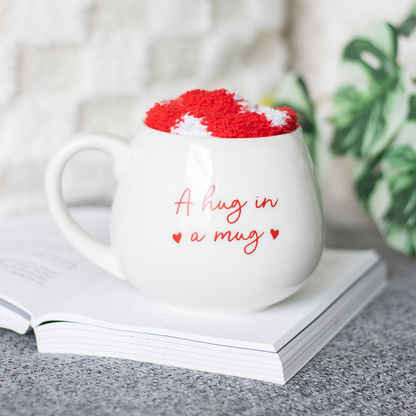 Hug In A Mug heart mug and sock set. A white mug with red writing saying 'A hug in a mug' and red fuzzy socks with white hearts making a wonderful gift.