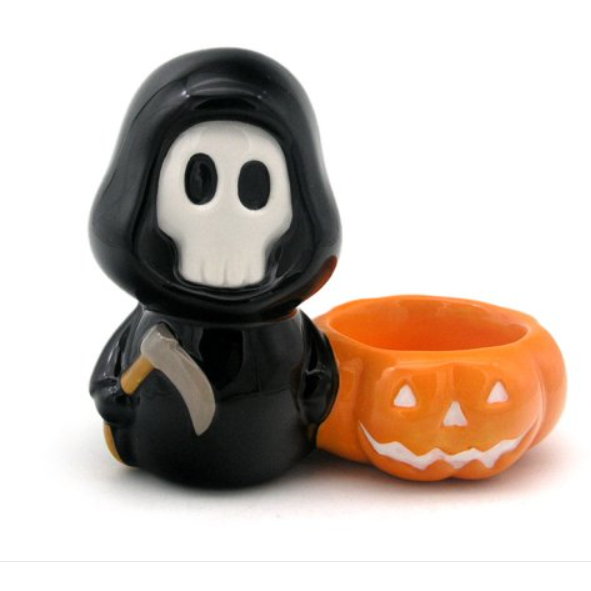 A cute little spooky skull boy tealight candle holder for your Halloween decorations, a skull faced, black robed creature holding a scythe and standing next to a happy carve faced pumpkin