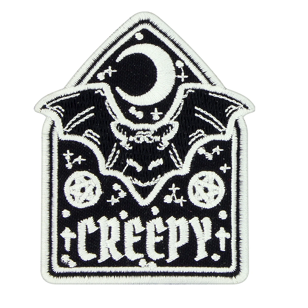 A monochromatic iron on patch featuring a crescent moon above a bat with two pentagrams and the word Creepy at the bottom