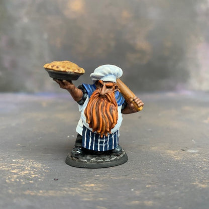 Tub the Dwarf Baker from the Reaper Miniatures Bones USA range pre painted by Mrs MLG.  This slightly grumpy looking baker has his wonderfully scrumptious pie in one hand and a rolling pin over his shoulder in the other, painted with blues and whites and sporting an elegant ginger beard. 