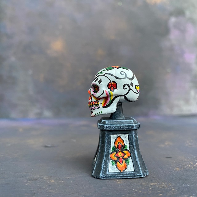 Prepainted Sugar Skull from the Reaper Miniatures bones USA range hand painted by Mrs MLG, a brightly coloured skull on a plinth. 