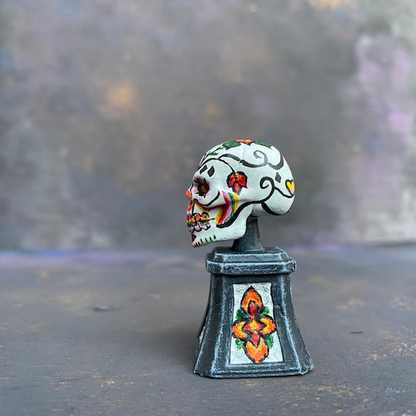 Prepainted Sugar Skull from the Reaper Miniatures bones USA range hand painted by Mrs MLG, a brightly coloured skull on a plinth. 