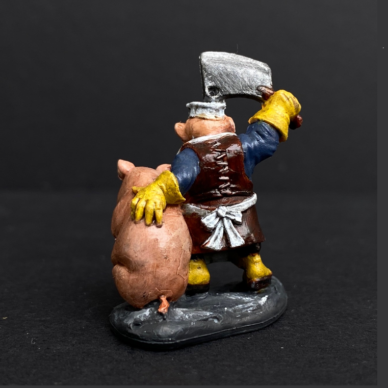 Hand painted dwarf butcher from the Reaper Miniatures range. Mrs MLG has painted this dwarf butcher with a yellow, blue and white colour scheme with a vibrant beard holding a clever above his head and a cute pig under his arm. 