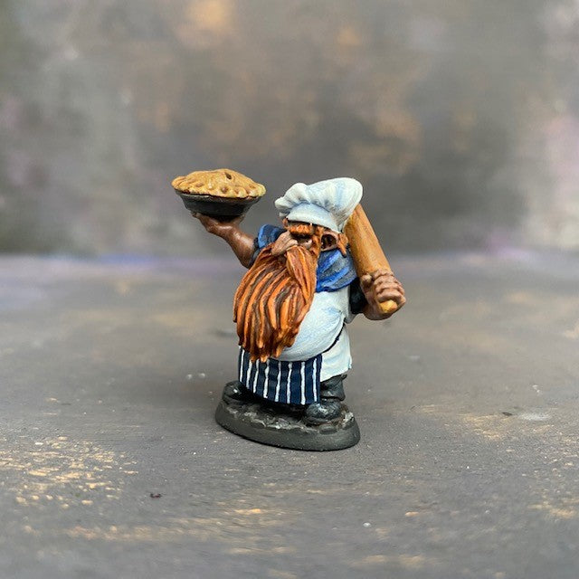 Tub the Dwarf Baker from the Reaper Miniatures Bones USA range pre painted by Mrs MLG.  This slightly grumpy looking baker has his wonderfully scrumptious pie in one hand and a rolling pin over his shoulder in the other, painted with blues and whites and sporting an elegant ginger beard. #