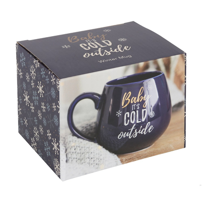 A beautiful rich blue rounded mug with gold and white writing saying 'Baby It's Cold Outside'.