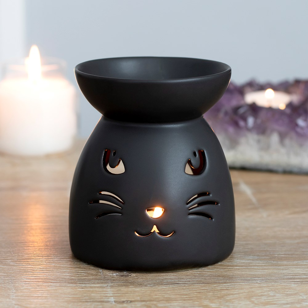 A matt black oil burner with a cut out cat face design