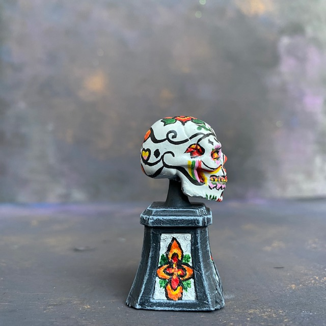 Prepainted Sugar Skull from the Reaper Miniatures bones USA range hand painted by Mrs MLG, a brightly coloured skull on a plinth. 