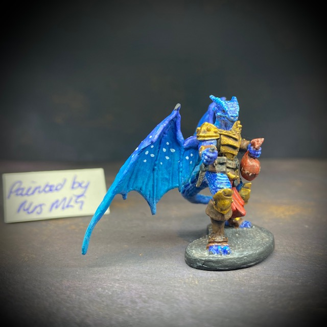  dragonfolk rouge holding a dagger in one hand and a pouch in the other. Mrs MLG has painted this miniature with a blue palette adding white dot effects to the wings, the armour is golden colour and Tazythas has a red loin cloth.