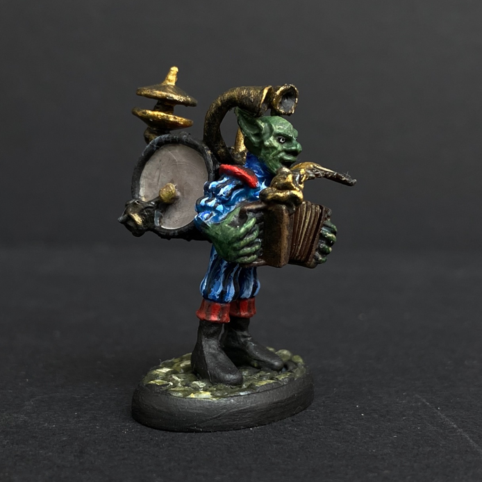 Hand painted one man band from the Reaper Miniatures range. Mrs MLG has painted this wonderful little goblin playing all his instruments for the one man band using a blue and red colour scheme for his clothing. 