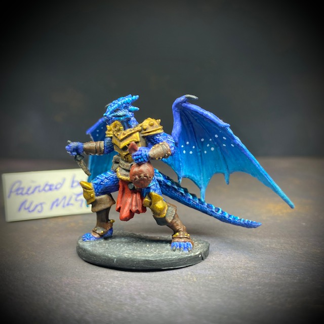  dragonfolk rouge holding a dagger in one hand and a pouch in the other. Mrs MLG has painted this miniature with a blue palette adding white dot effects to the wings, the armour is golden colour and Tazythas has a red loin cloth.