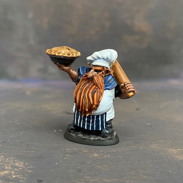 Tub the Dwarf Baker from the Reaper Miniatures Bones USA range pre painted by Mrs MLG.  This slightly grumpy looking baker has his wonderfully scrumptious pie in one hand and a rolling pin over his shoulder in the other, painted with blues and whites and sporting an elegant ginger beard. 