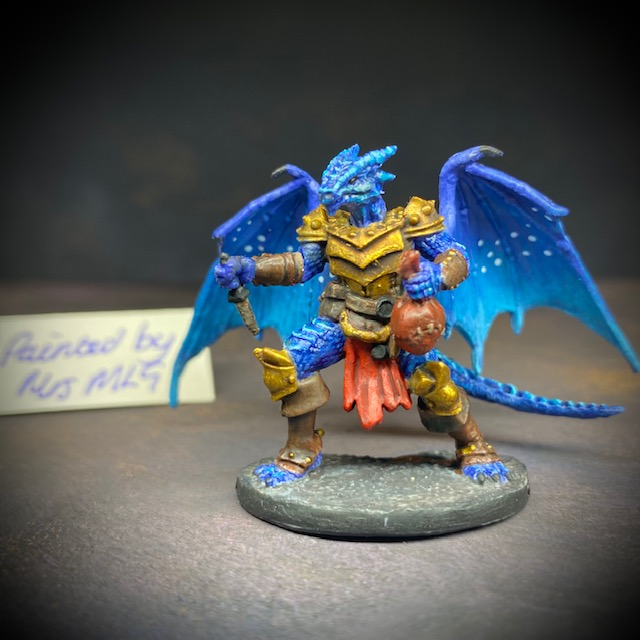  dragonfolk rouge holding a dagger in one hand and a pouch in the other. Mrs MLG has painted this miniature with a blue palette adding white dot effects to the wings, the armour is golden colour and Tazythas has a red loin cloth.