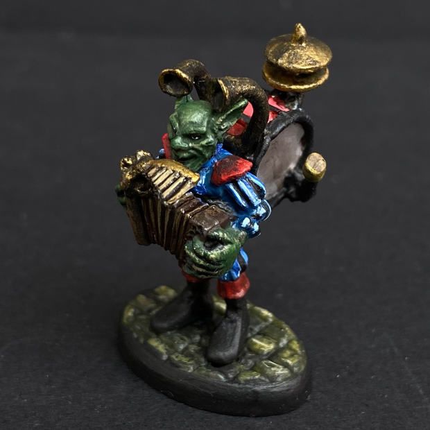 Hand painted one man band from the Reaper Miniatures range. Mrs MLG has painted this wonderful little goblin playing all his instruments for the one man band using a blue and red colour scheme for his clothing. 